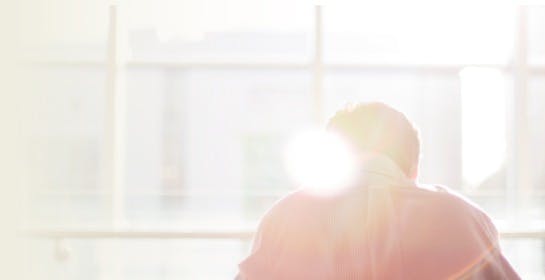 man sitting in front of the window with the sunlight shining in