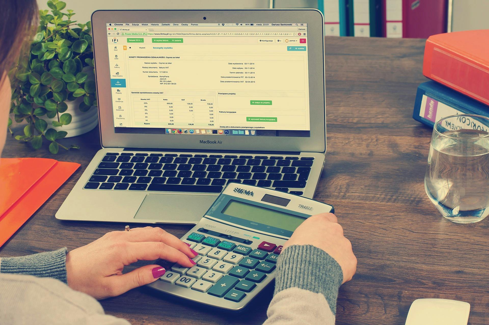 woman using calculator with her computer in the background