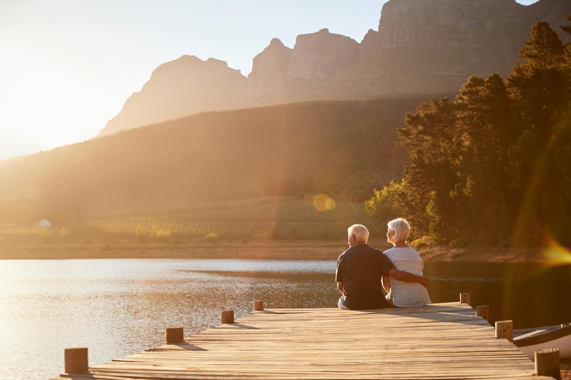 man with his arm around woman sitting on the end of the dock