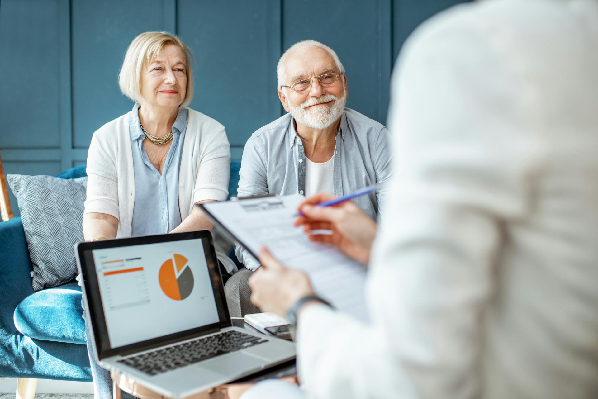 couple smiling at a lady reviewing financial plans