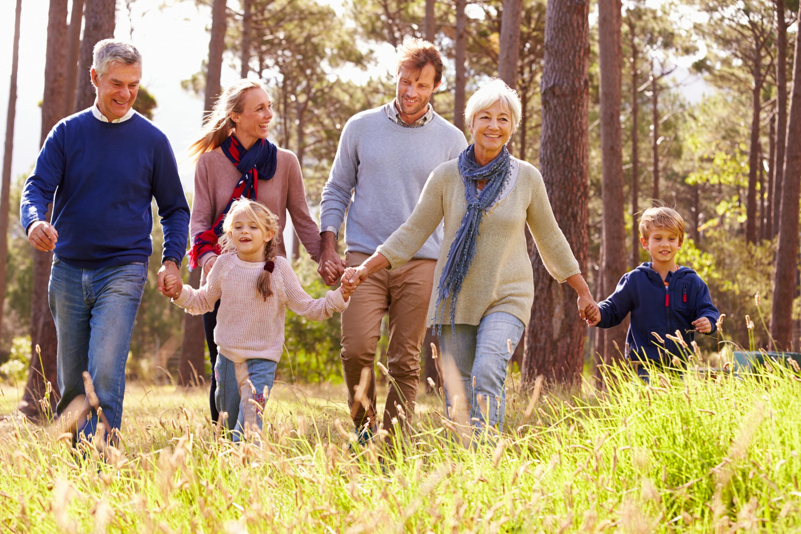 A happy family with grandparents, parents, and children walking in the countryside