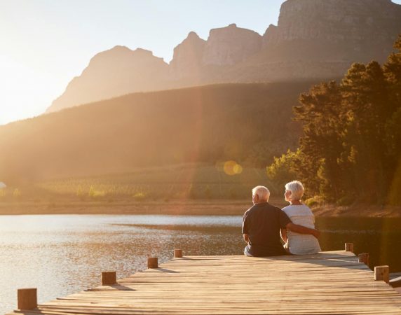 man with his arm around woman sitting on the end of the dock