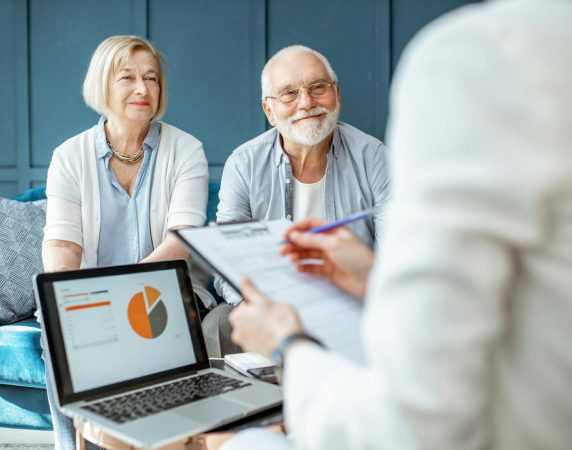 couple smiling at a lady reviewing financial plans