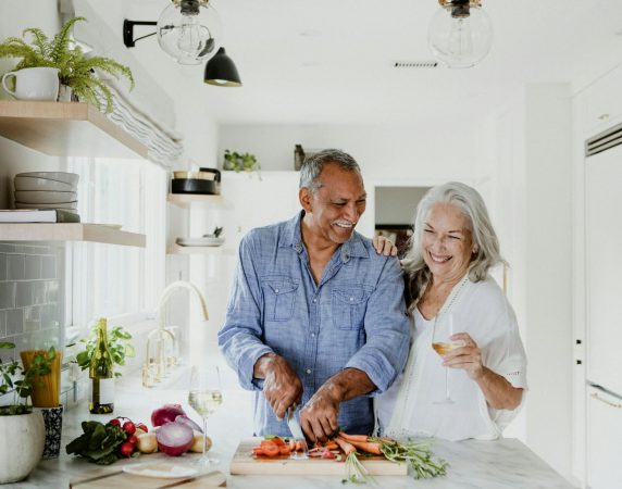 couple laughing while cooking together in the kitchen