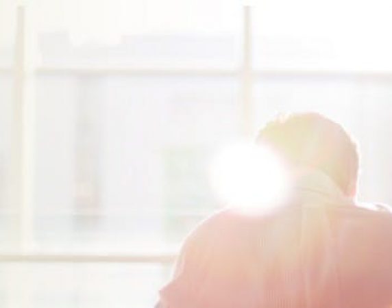 man sitting in front of the window with the sunlight shining in