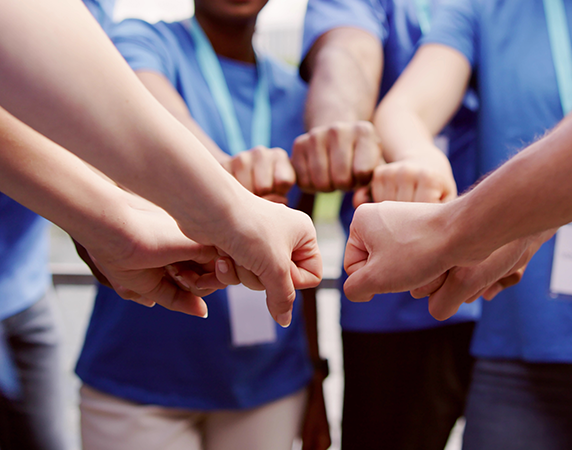 group of people with their fist out making a circle