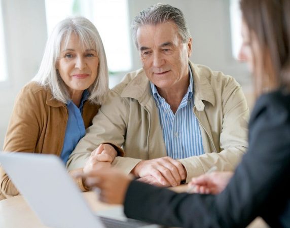 couple with linked arms smiling looking at a computer screen